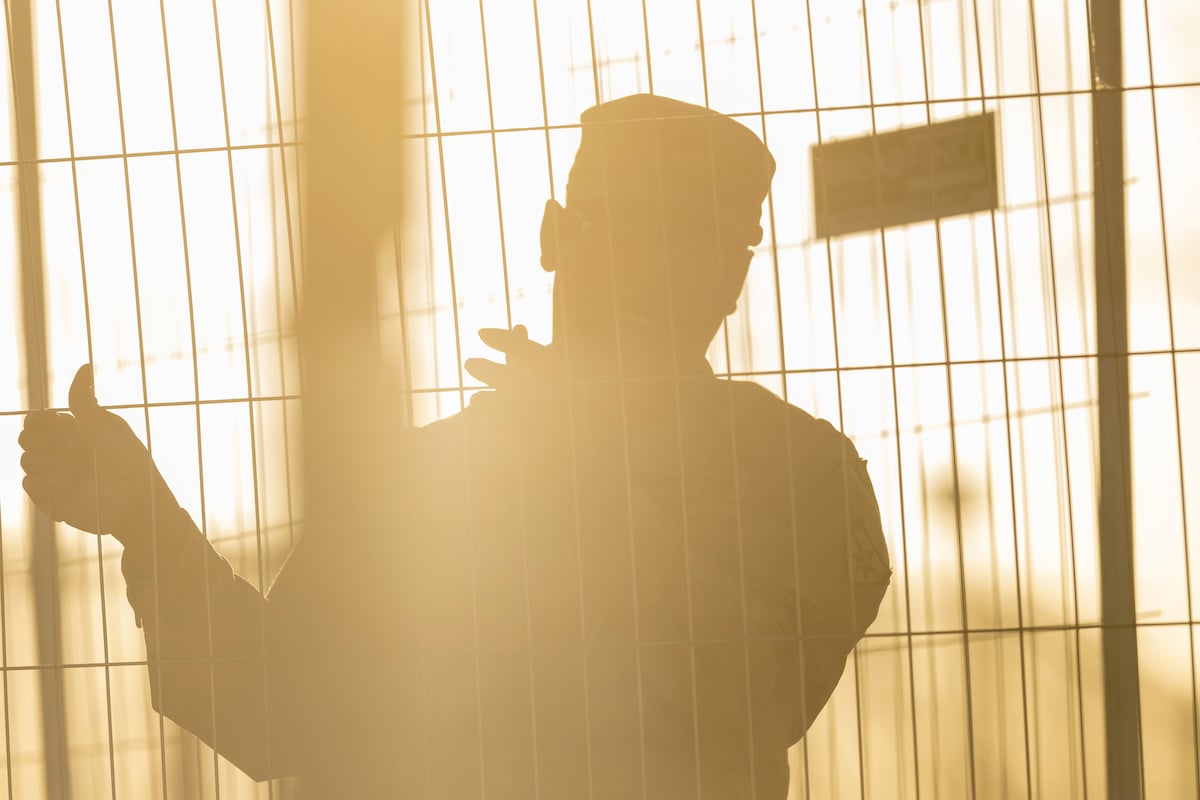 The silhouette of a border agent at a wire fence.