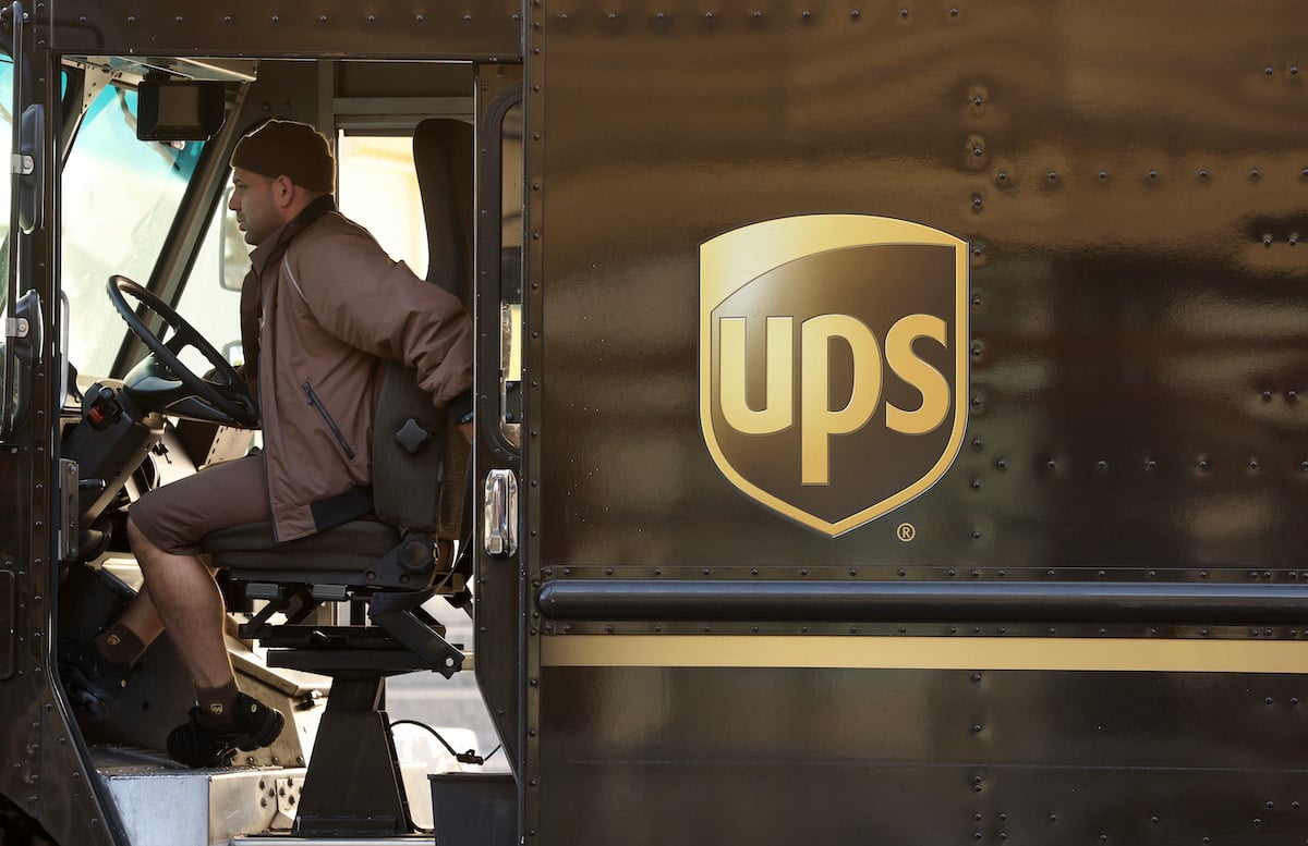 A UPS driver sits in the driver's seat of a UPS truck
