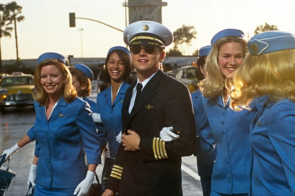 Leonardo DiCaprio dressed as Pan Am pilot surrounded by flight attendants in Catch Me If You Can