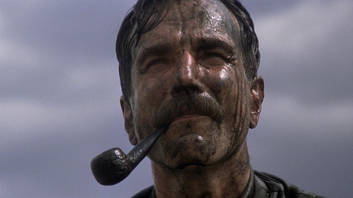 Pipe in mouth and head covered in oil, Daniel Plainview (Daniel Day-Lewis) enjoys his success in There Will Be Blood. 