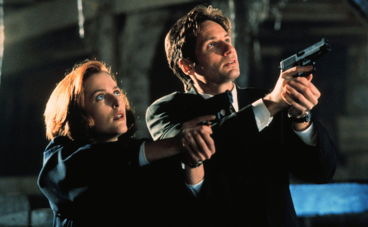 Agents Dana Scully (Gillian Anderson) and Fox Mulder (David Duchovny) in 'The X-Files': A woman and a man stand with guns pointed upward at an unseen target.