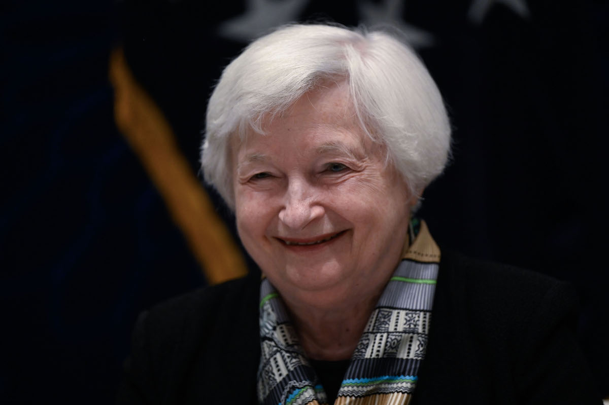 Janet Yellen from the shoulders up, against a black background, smiling.
