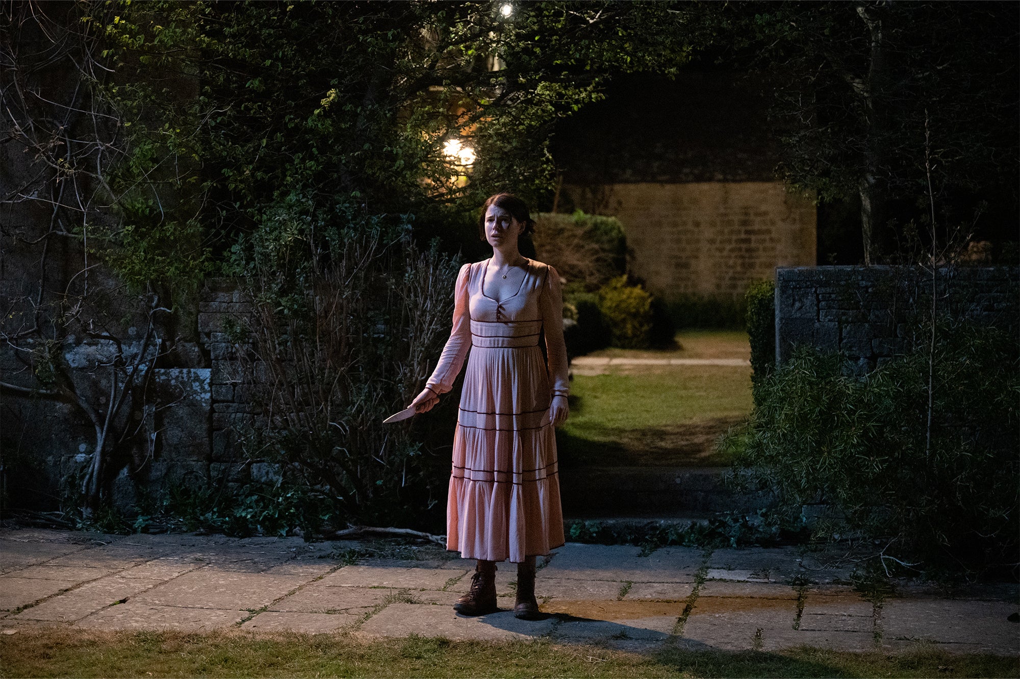 Harper (Jessie Buckley) stands in a countryside garden, armed with a knife in ‘Men.’ 