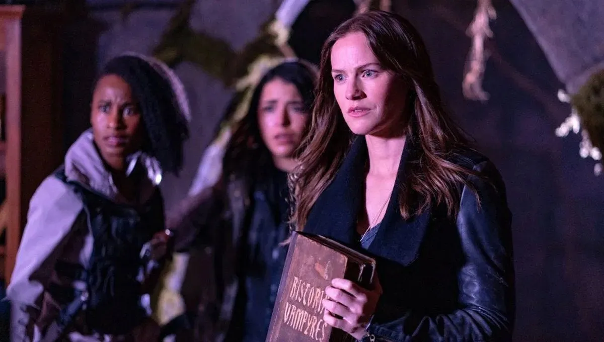 A brunette named Vanessa Van Helsing (Kelly Overton) holding an ancient book in Van Helsing
