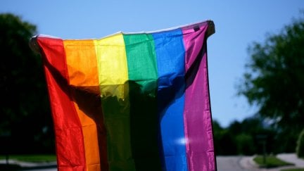 A person is seen holding up a rainbow Pride flag