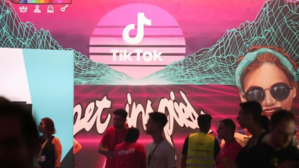 Gamers and Staff at a con standing in front a screen that has 