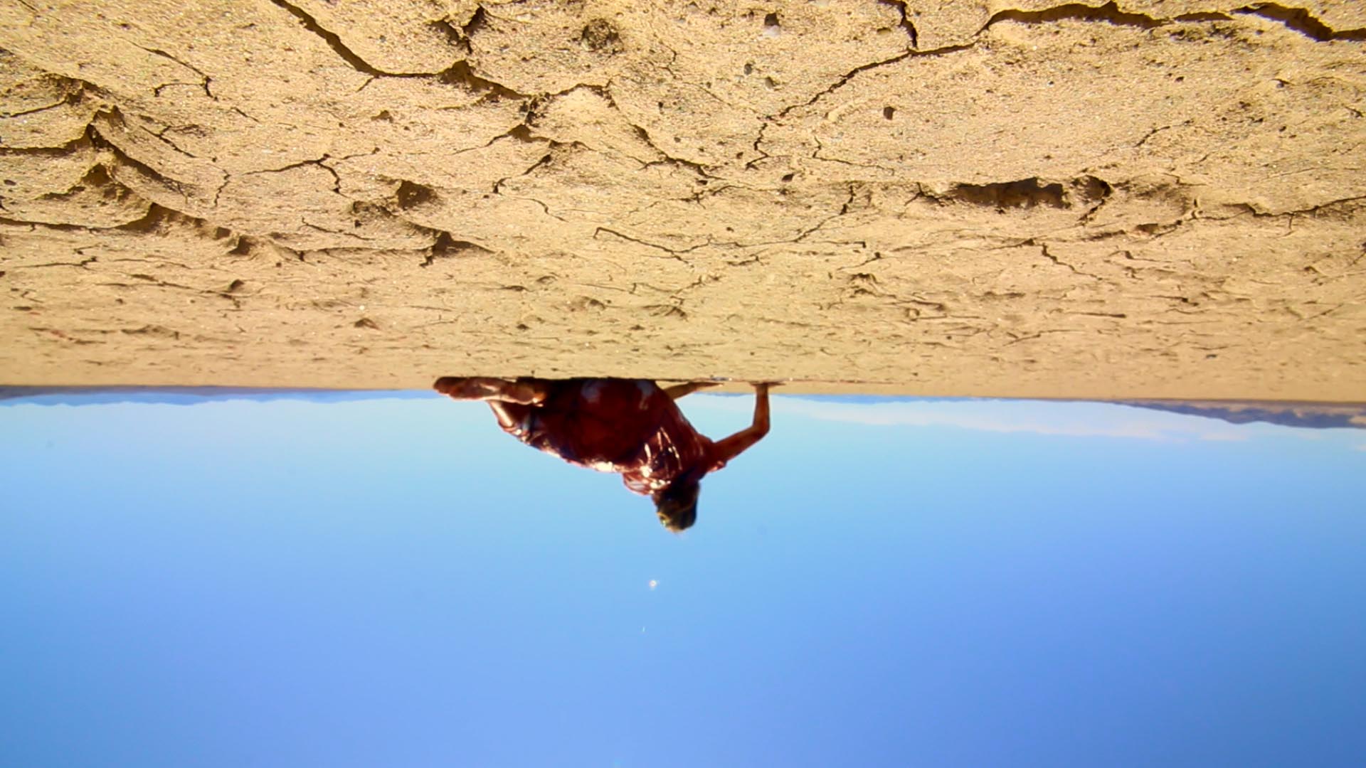 An upside-down image of a woman (Michelle May) in a bloodied white dress as she crawls across the Mojave desert in ‘The Outwaters.’ 
