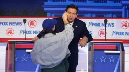 Ron DeSantis gets makeup applied at his podium during a commercial break during the Republican Primary Debate