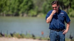 Ron DeSantis stands in front of the Rio Grande, looking grim.