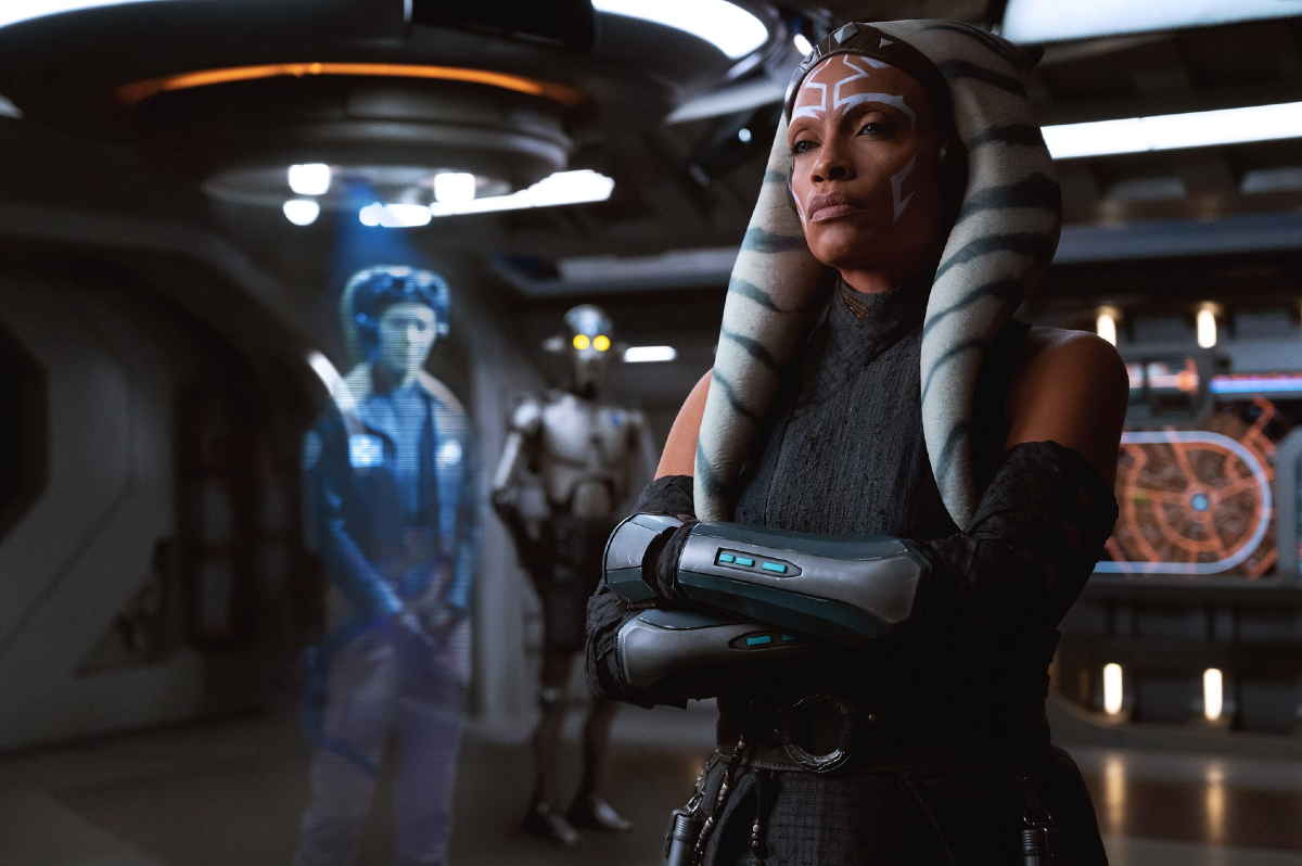 Ahsoka Tano (Rosario Dawson) stands with arms folded, looking at a hologram image of Hera Syndulla (Mary Elizabeth Winstead) in the live-action Star Wars series 'Ahsoka'