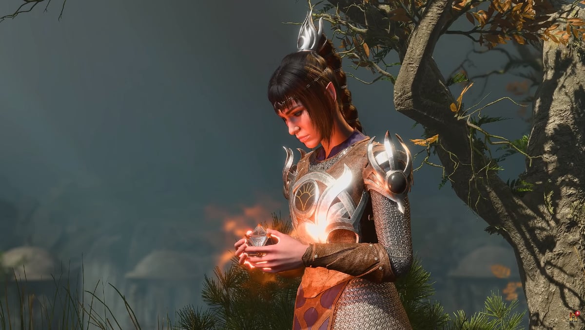 Shadowheart in 'Baldur's Gate 3': A dark-haired Cleric woman in silver armor looks down at a glowing object in her hands