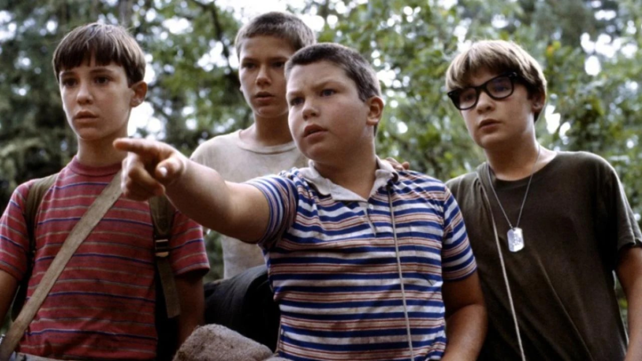 Four young white boys in the woods looking curiously into the distance in "Stand By Me" 