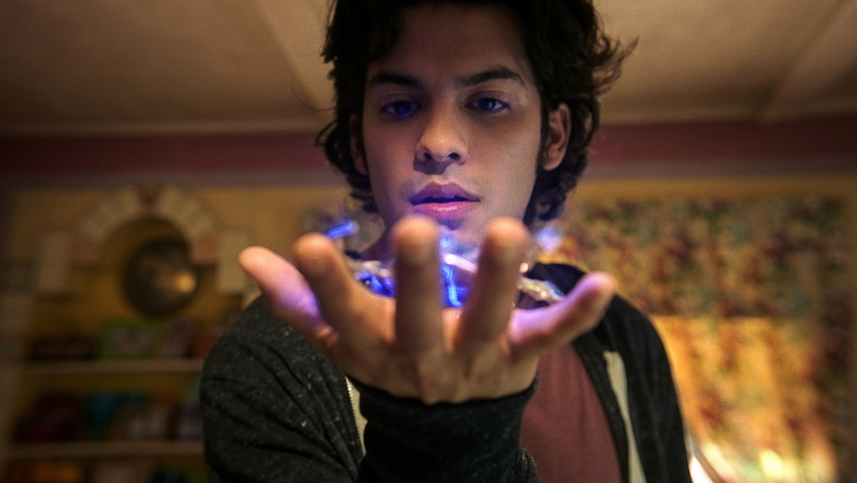 Xolo Maridueña as Jaime Reyes in 'Blue Beetle': A young man gazes at a glowing blue scarab in his hand
