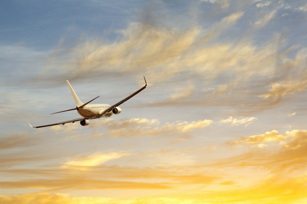 An airplane flying into a sunset.