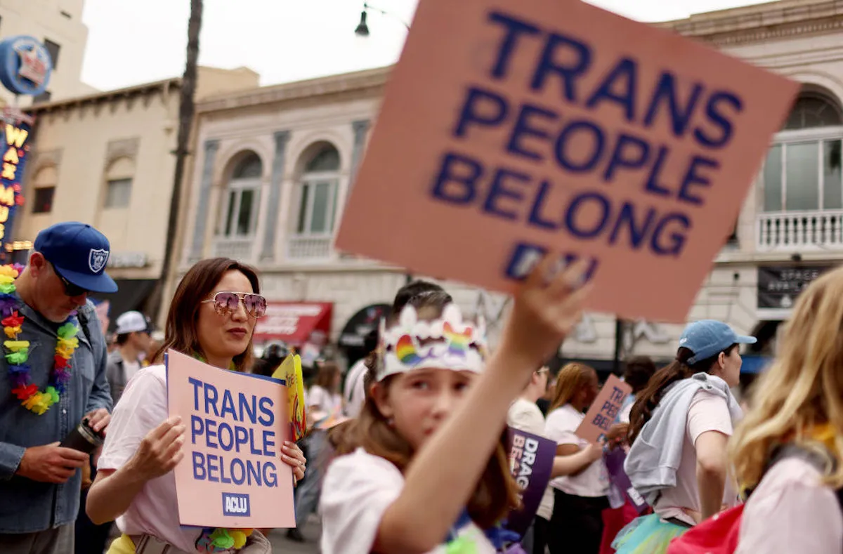 A trans rights protest, with demonstrators holding signs reading "trans people belong"