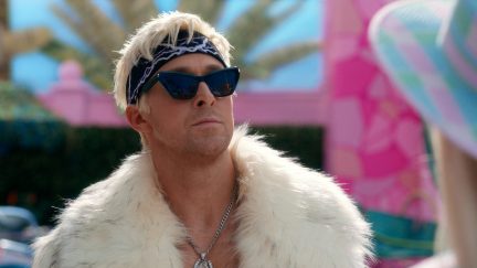 Ryan Gosling as Ken in the movie Barbie, wearing a white fur coat and sunglasses, mugging.