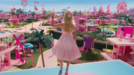 In a scene from Barbie, Barbie is seen from behind, waving to Barbieland from her balcony.