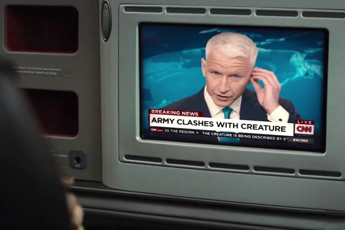 Anderson Cooper on CNN seen on a small TV screen above a chyron reading "Army clashes with creature" in a still from Batman v. Superman.