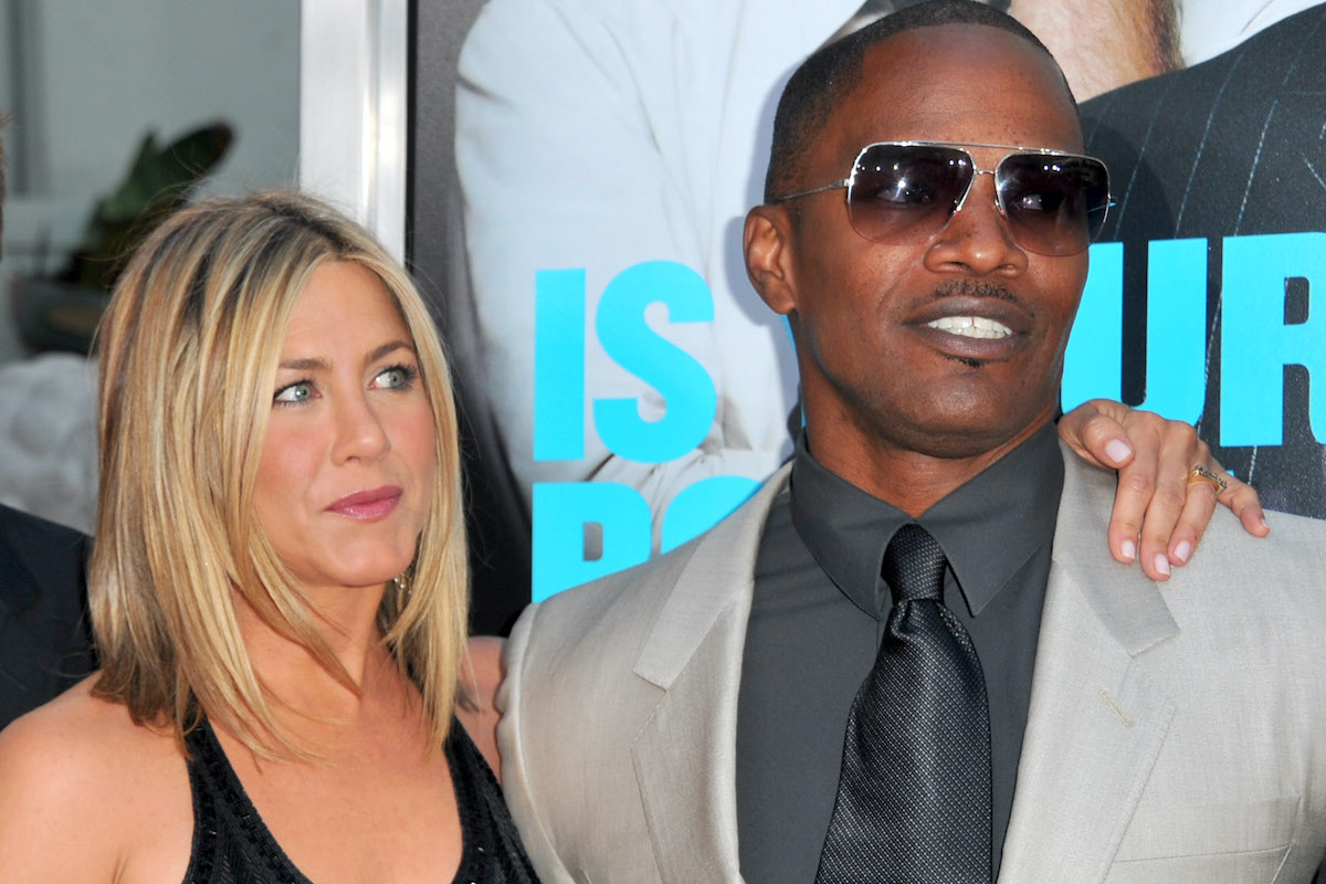 Jennifer Aniston and Jamie Foxx stand together on a red carpet taking photos.
