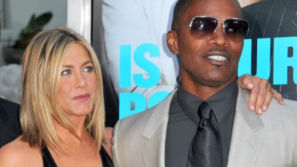 Jennifer Aniston and Jamie Foxx stand together on a red carpet taking photos.