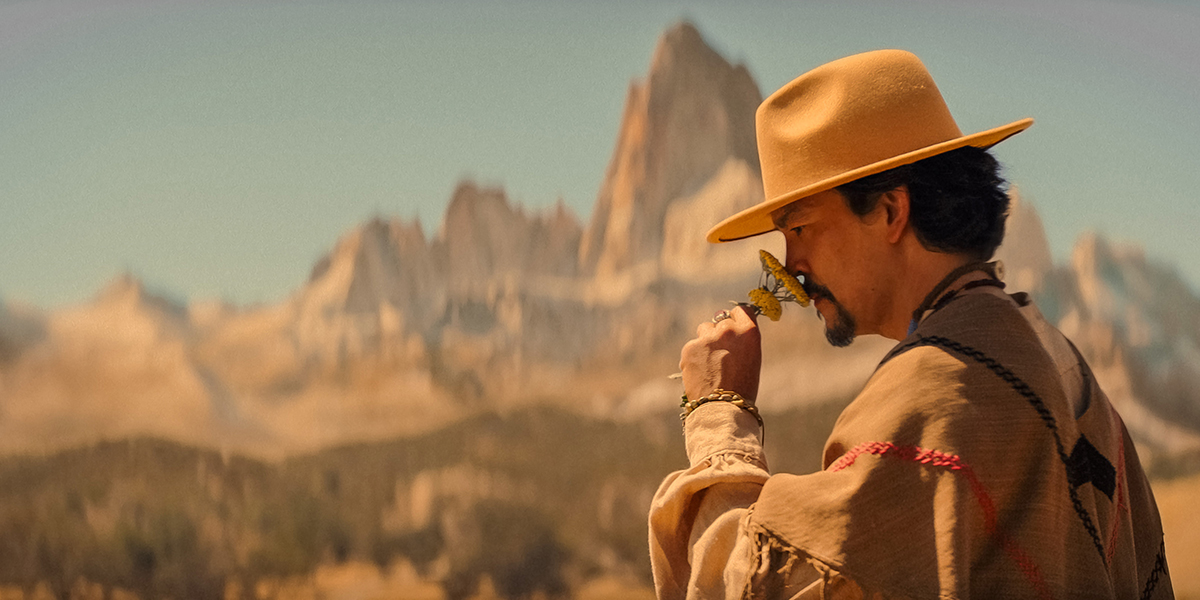 John Cho sniffing a flower in the desert as Ulysses in "The Afterparty"