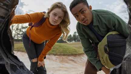 Two kids looking into a hole in Landscape With Invisible Hand