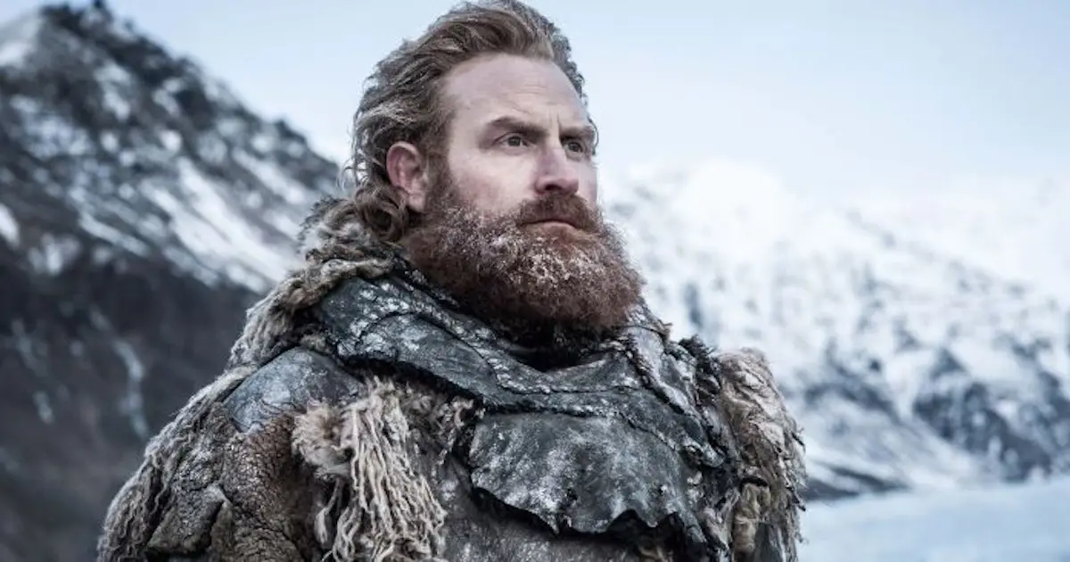 Tormund Giantsbane in "Game of Thrones" surrounded by snow covered mountains wearing multiple furs staring into the distance.