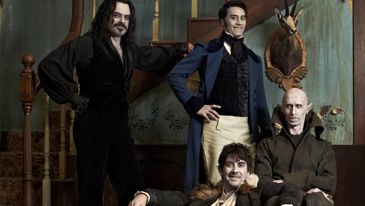 The cast of "What We Do In The Shadows" standing in a gothic parlor.