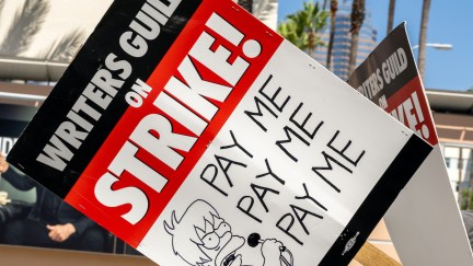 A WGA strike picket sign featuring a Simpsons-style drawing reading 