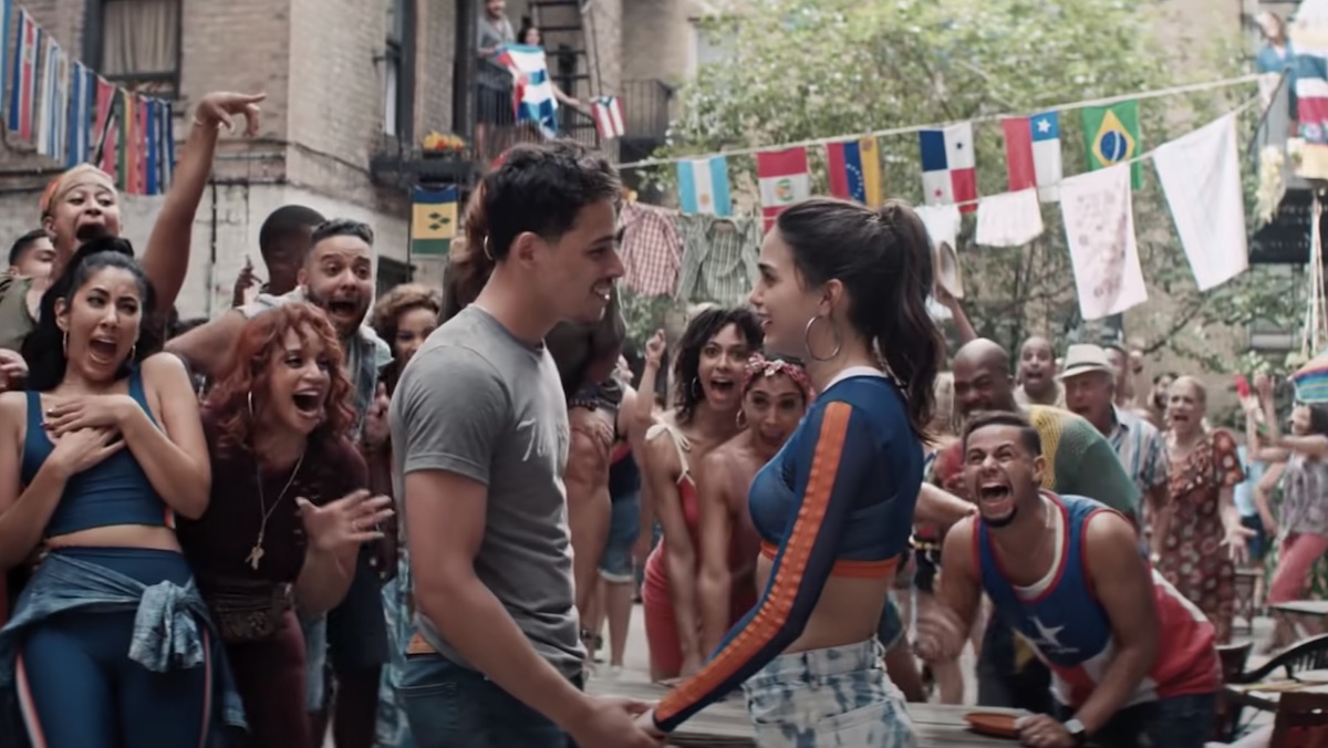 Anthony Ramos and Melissa Barrera hold hands in a crowd in a scene from 'In the Heights.' 