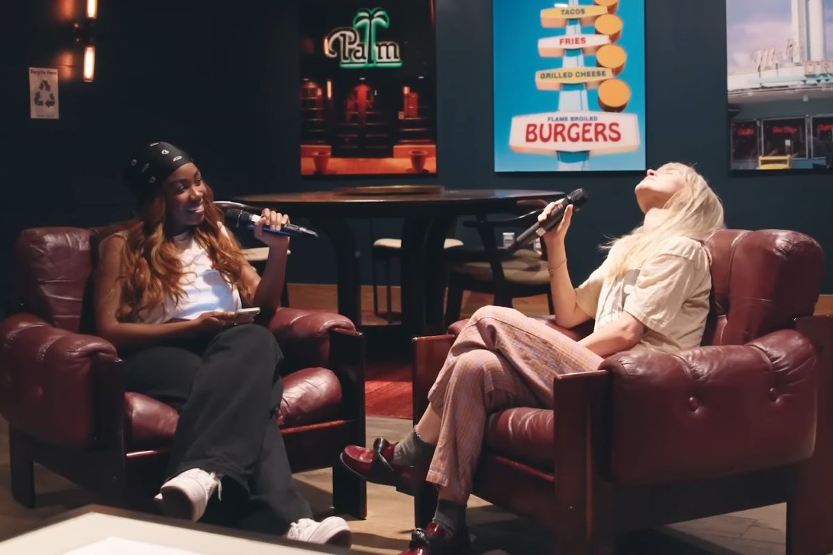 Sequoia Holmes interviewing Hayley Williams on a set with two armchairs. 