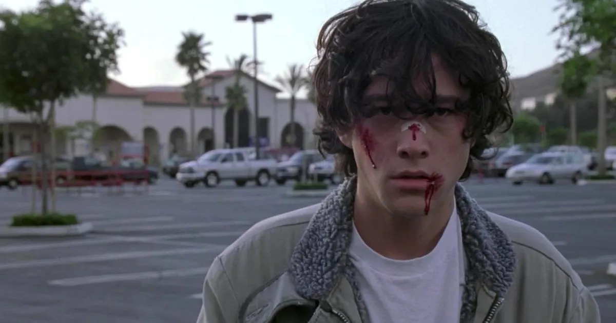 A boy with.a bloody face standing in a parking lot in "Brick"