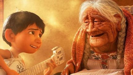 Miguel (12 year old Mexican boy) plays guitar for his smiling grandmother, Coco (elderly Mexican woman) in a scene from the Pixar film, 'Coco.'