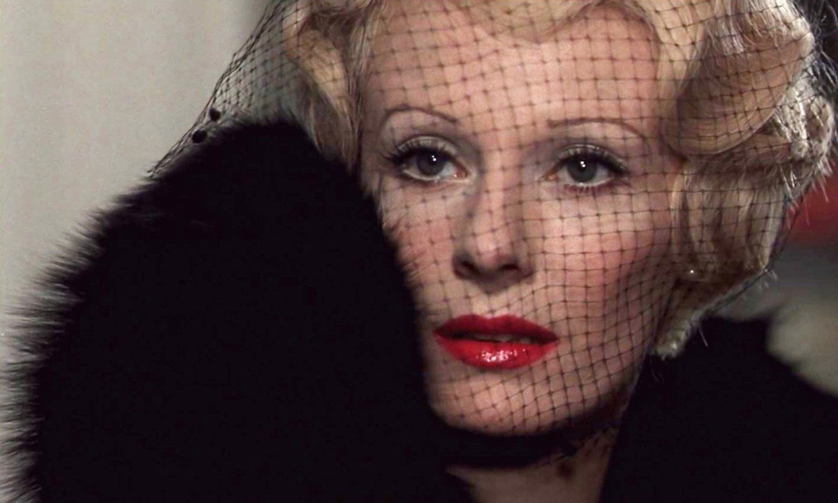 A glamorous blonde Countess Elizabeth Bathory (Delphine Seyrig) peeks out from a veiled fascinator hat and a fur coat in ‘Daughters of Darkness.’