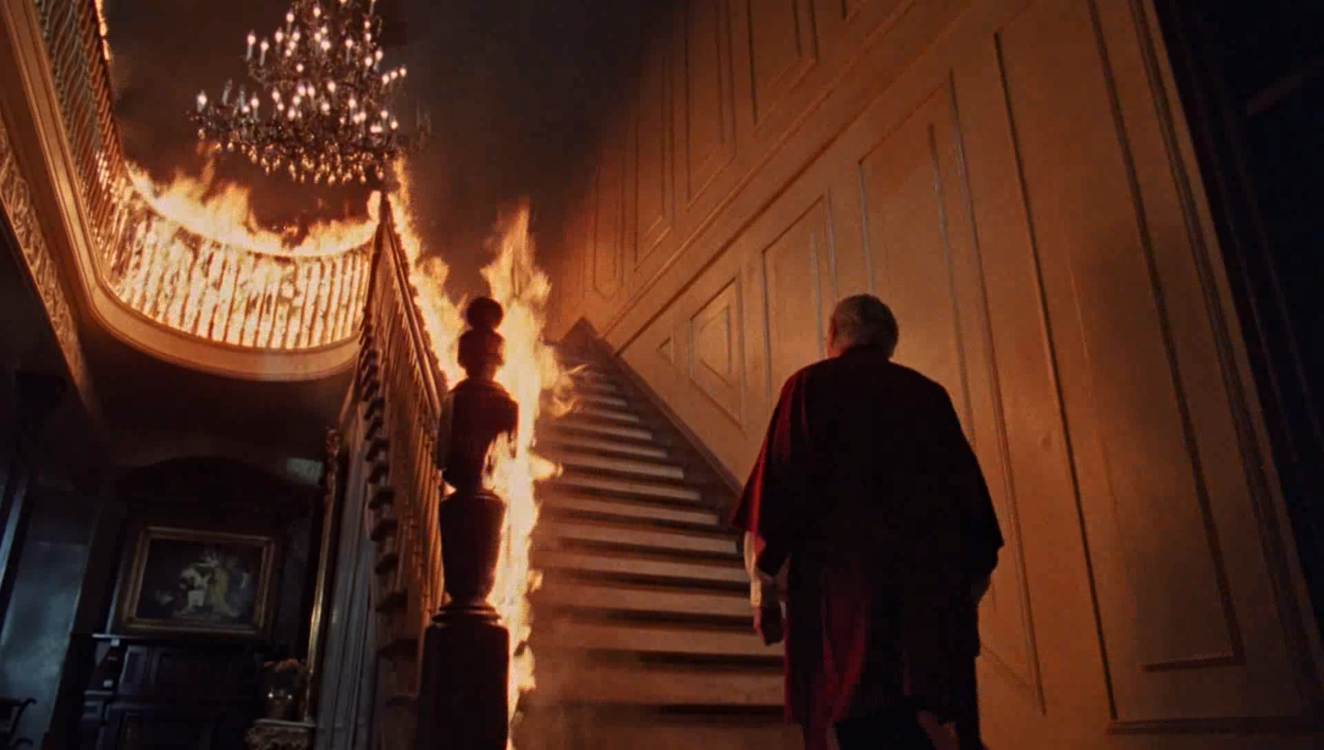 Dressed in a maroon bathrobe and pajamas, John Russell (George C. Scott) looks up at the flaming staircase of his home in ‘The Changeling.’