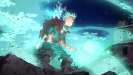 Midoriya stands in rubble wearing ripped up clothes, glowing green with power in 