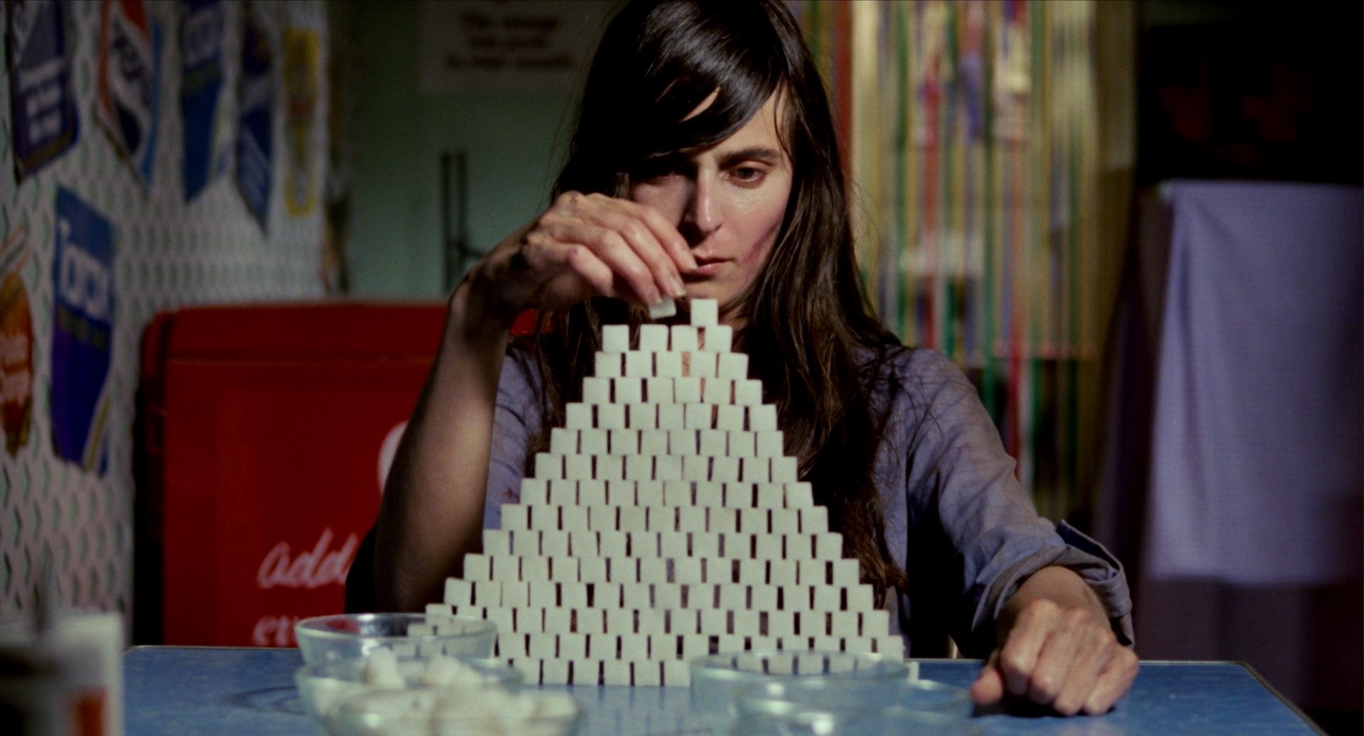 A frazzled and traumatized Linda Stevens (Jacki Kerin) dissociatively builds a pyramid out of sugar cubes in ‘Next of Kin.’ 