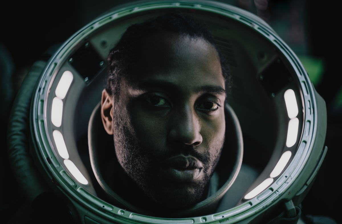 Joshua (John David Washington) stares at the camera in The Creator, wearing a space suit with no helmet.