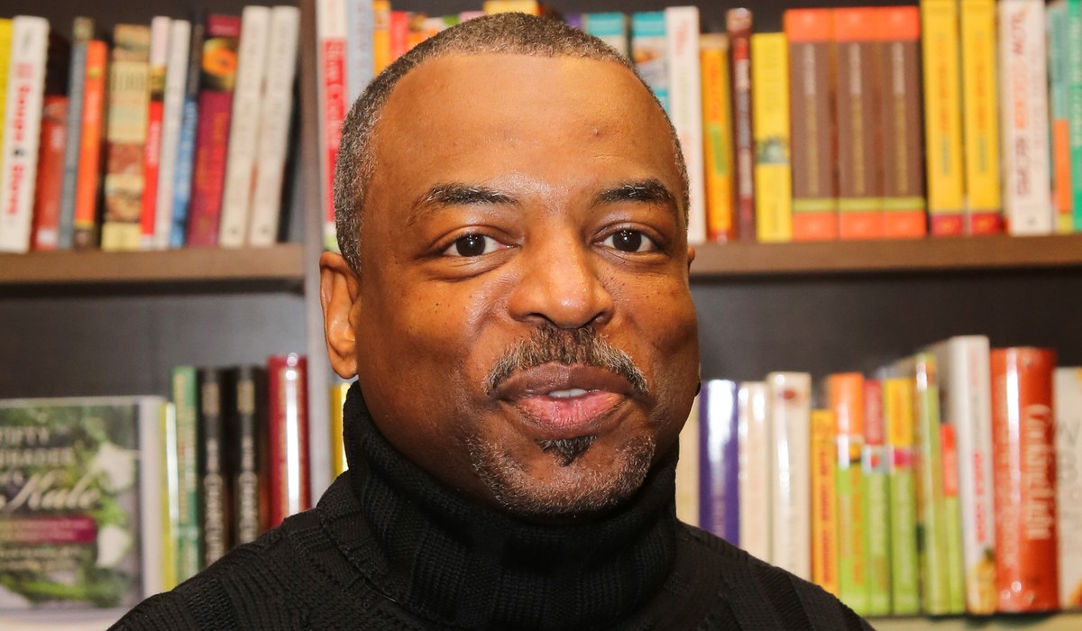 LeVar Burton posing next to books for a book signing