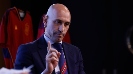 Luis Rubiales speaks and holds one finger up.