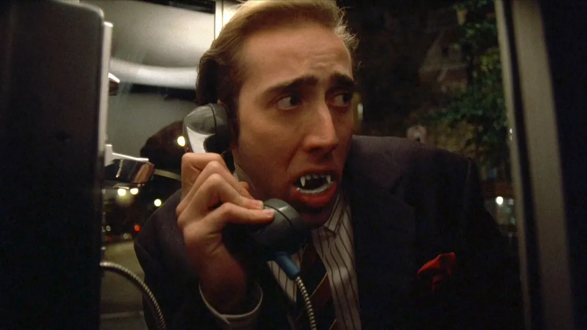 Nicolas Cage wearing fake teeth inside a phone booth in 'Vampire's Kiss.'
