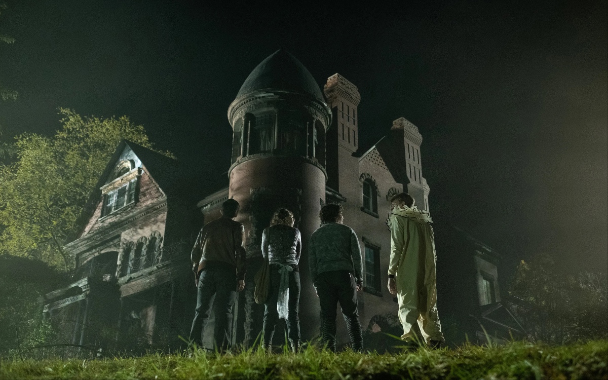 Image from Scary Stories to Tell in the Dark: Four kids in Halloween costumes look at a haunted house