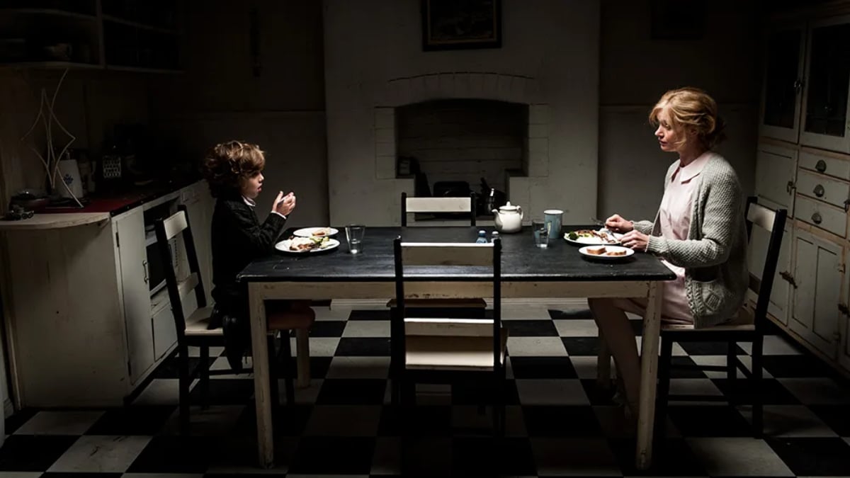 Amelia (Essie Davis) and Samuel (Noah Wiseman) sit opposite each other at a dinner table in 'The Babadook'
