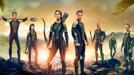 A group of seven people wear uniforms and hold various weapons in 'The Hunger Games: Catching Fire.'