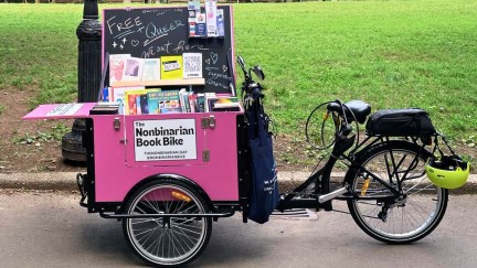 The Nonbinarian Book Bike, a retrofitted bicycle carrying a big box of queer books.