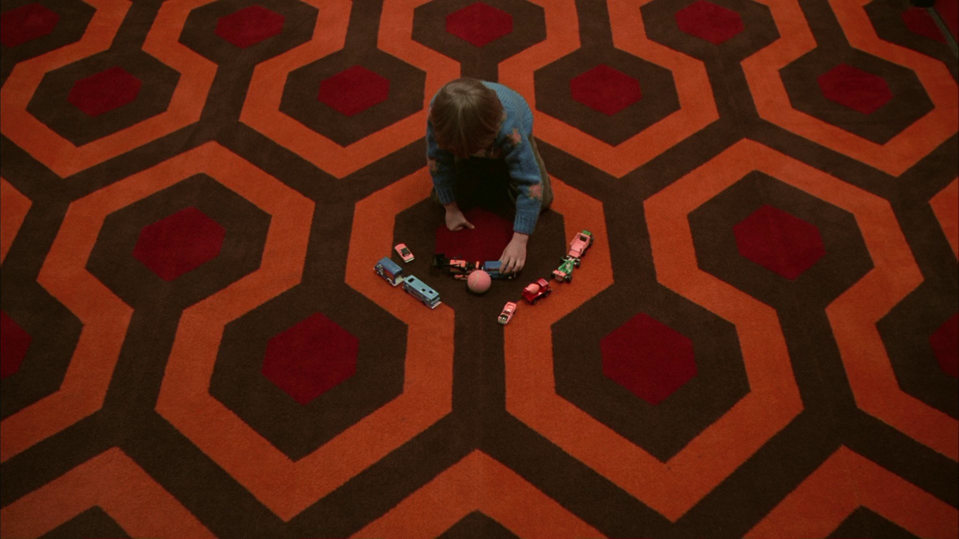 A young boy, Danny “Doc” Torrance (Danny Lloyd) plays with toy cars on the geometric Overlook Hotel carpet as a ball mysteriously rolls toward him in ‘The Shining.’ 