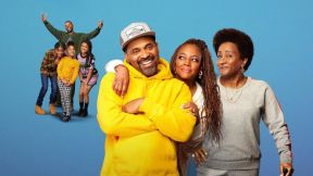 A Black family of 7 smiling at the camera from the the sitcom 'The Upshaws