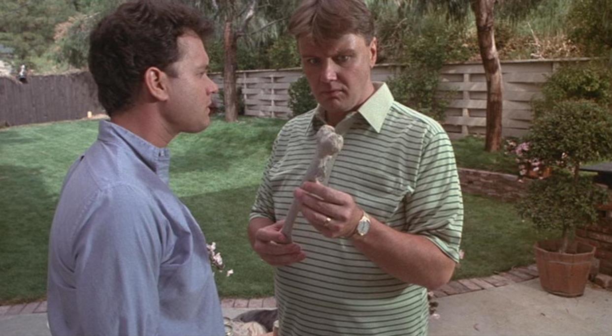 Sububanites Ray and Art (Tom Hanks and Rick Ducommun) study what appears to be a human bone in ‘The Burbs.’ 
