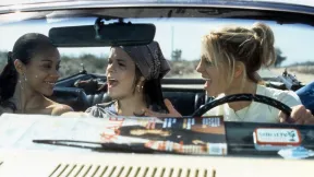 Image of Zoe Saldana, Taryn Manning, and Britney Spears in a scene from 'Crossroads.' They are sitting across the front seat of a convertible smiling and singing as Spears drives.