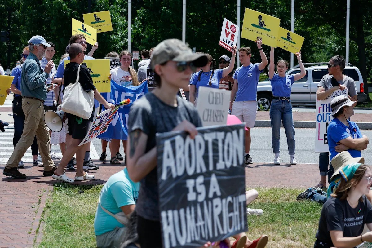 An abortion rights protester stands with a group of anti-abortion protesters behind her.